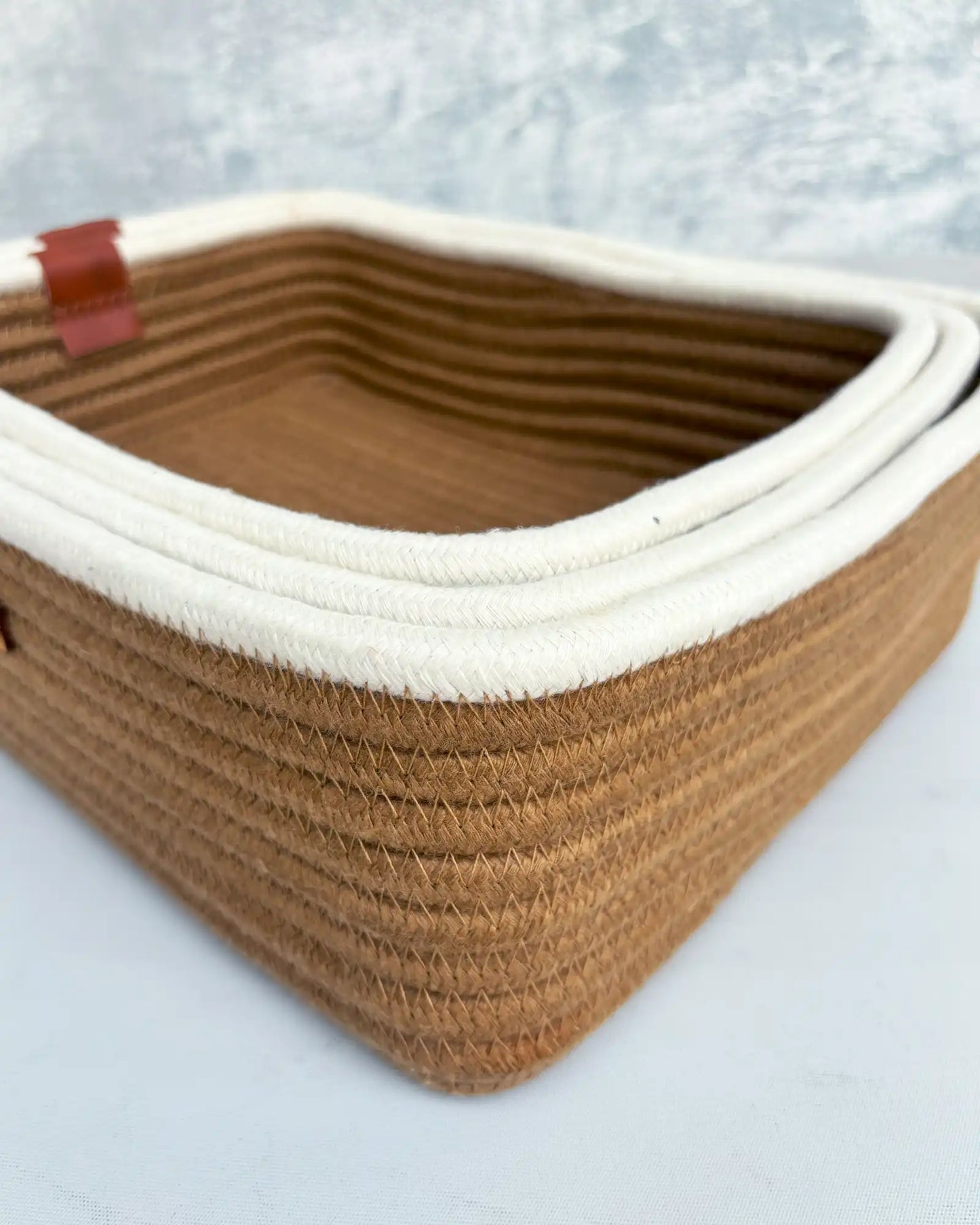 Woven basket with a white rim on a light gray background