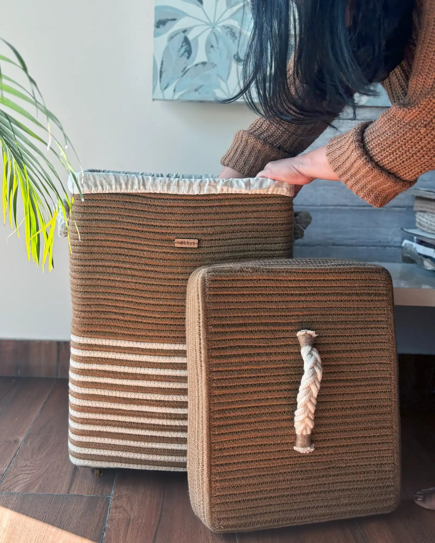Woven storage baskets with a rope handle on a wooden floor.